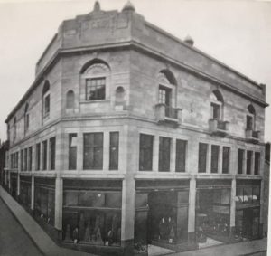Photo showing Unitas Hall and shops, east corner of Queen Anne Street and Randolph Street.