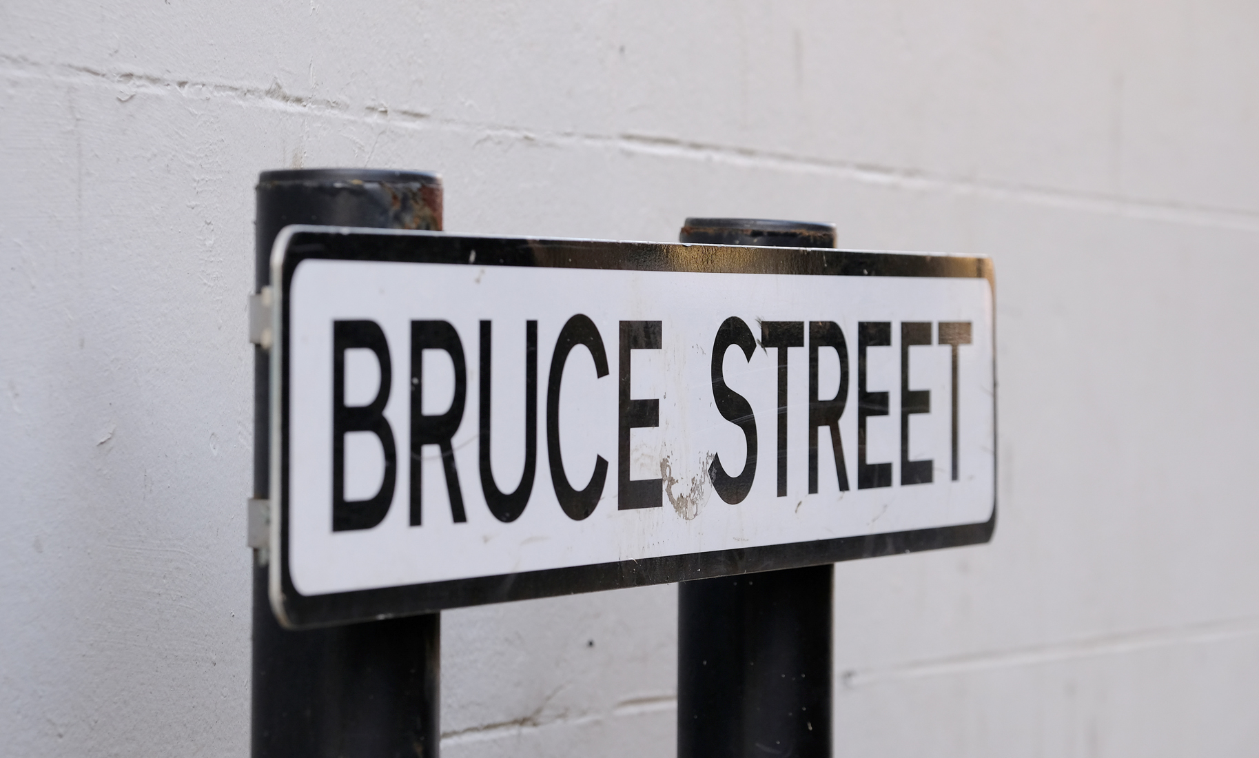 Street sign white background, black writing with Bruce Street.